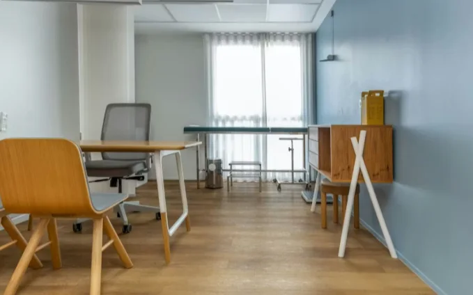 Consultório com mesa, cadeiras e janela ampla